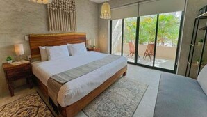 A spacious bedroom with a large bed, a ceiling fan, and a view of the outdoors through a sliding glass door. - Agata 4, Design and Comfort in Every Corner-2 (Tulum)