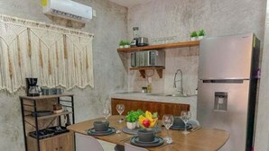 A compact kitchen with a wooden dining table, grey chairs, and a built-in oven. - Agata 4, Design and Comfort in Every Corner-2 (Tulum)