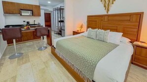 A hotel room with a large bed, a desk, and a chair. There is a wooden headboard and a wall-mounted decoration. - NAIA C19, Increible Studio Con Jacuzzi (Tulum)