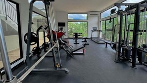 A spacious gym with various exercise equipment, large windows, and a view of greenery outside. - NAIA C19, Increible Studio Con Jacuzzi (Tulum)