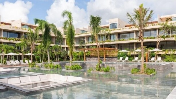 Um hotel moderno com área de piscina, várias varandas e vegetação exuberante.