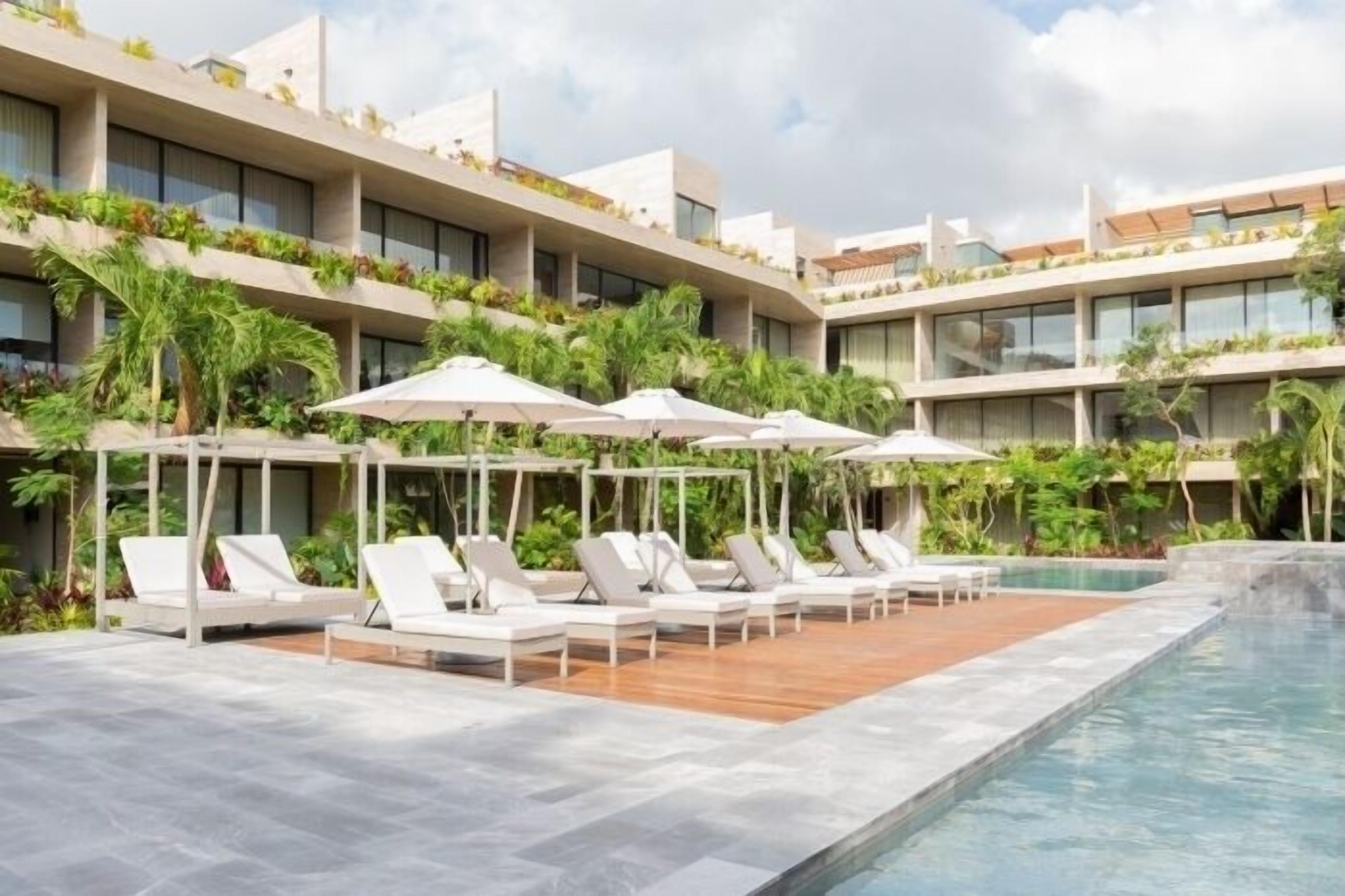 A modern hotel with a rooftop pool area featuring sun loungers and umbrellas.