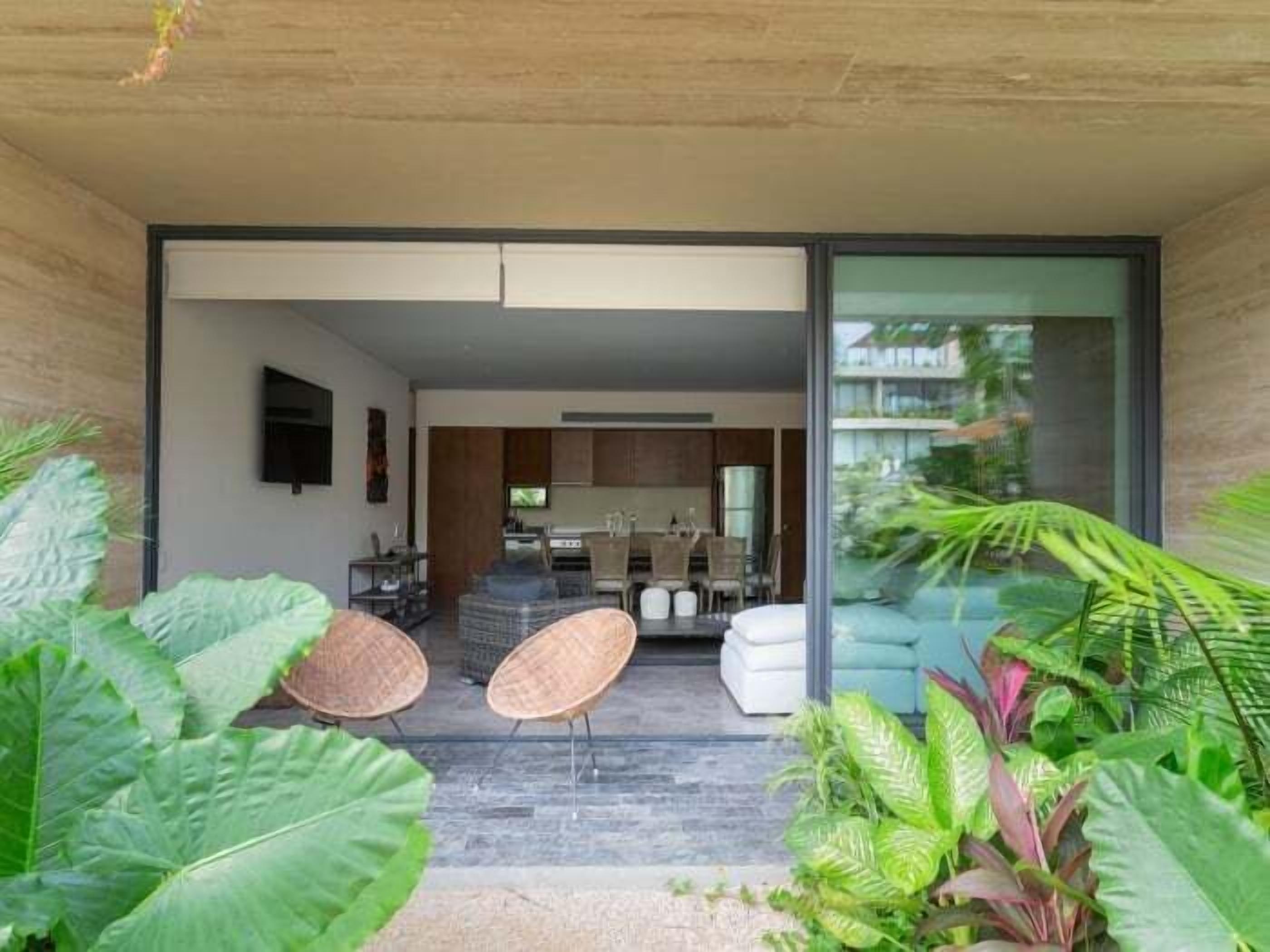 Un intérieur moderne comprenant un coin repas, une cuisine et une porte vitrée donnant sur un balcon agrémenté de plantes.