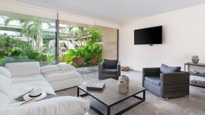 Ein modernes Wohnzimmer mit einer großen Glaswand, einem Flachbildfernseher und einer gemütlichen Sitzecke.