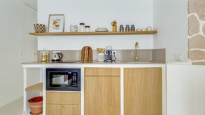 A compact kitchenette with a microwave, coffee maker, and storage cabinets.