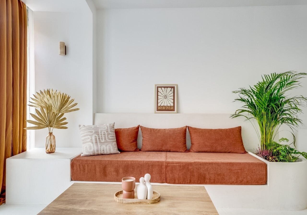 Una sala de estar moderna con un sofá, una mesita auxiliar, una planta en maceta y una obra de arte colgada en la pared.