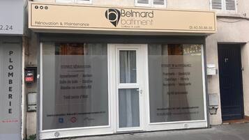 Une devanture de magasin avec une enseigne indiquant « Belard bâtiment », proposant des services de rénovation et d’entretien.