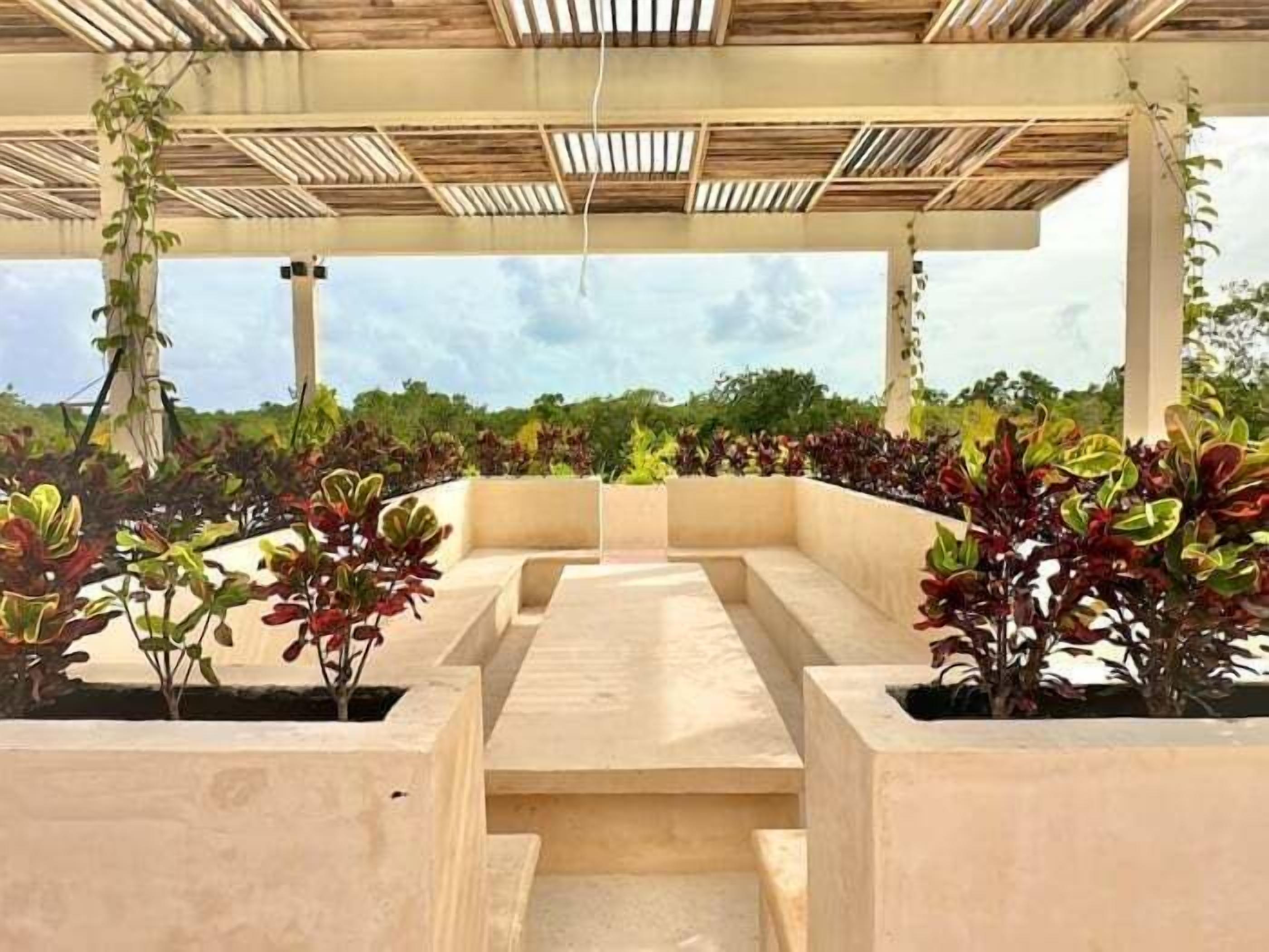 An outdoor seating area with concrete planters and a wooden ceiling structure.