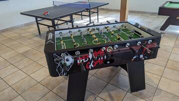Een tafelvoetbaltafel met een net in het doel en een pingpongtafel op de achtergrond.