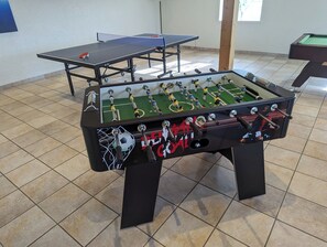 A foosball table with a netted goal area and a table tennis table in the background. - Hanklit holiday home, event & course venue (Nykøbing M)