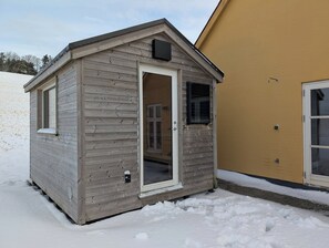 A small wooden structure with a door, windows, and a vent. - Hanklit holiday home, event & course venue (Nykøbing M)