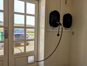 A door with a view of parked cars outside, a wall-mounted intercom system, and a power outlet. - Hanklit holiday home, event & course venue (Nykøbing M)
