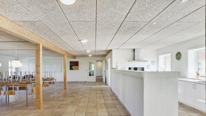 Tilava hotellin aula, jossa on pitkä vastaanottotiski, puiset pylväät ja laatoitettu lattia.