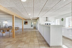 Un amplio vestíbulo de hotel con una larga recepción, pilares de madera y suelo de baldosas.