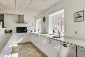 Una cocina moderna con armarios blancos, un lavamanos de acero inoxidable y un lavavajillas.