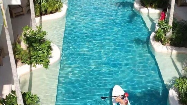 A person kayaking in a clear blue pool with palm trees and white circular islands. - COCAY PI 2223,Sumérgete en Tranquilidad&Belleza (Tulum)