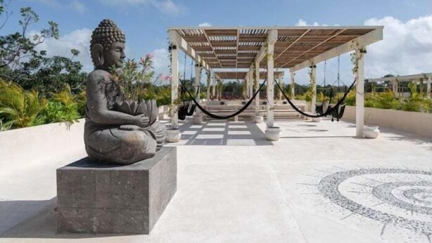 Una statua di Buddha in posizione meditativa, un padiglione coperto e un pavimento decorato.