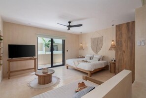 Un dormitorio moderno con una cama, televisor, ventilador de techo y un amplio ventanal.