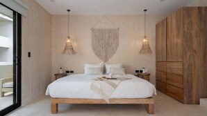 Een moderne slaapkamer met een groot bed, twee nachtkastjes en een houten garderobe.