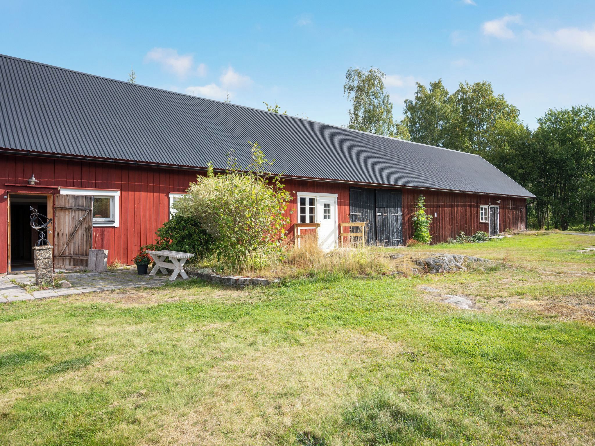 Une grange rouge avec un toit en métal, une porte en bois et une petite table au premier plan.
