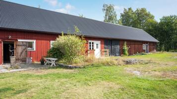 Une grange rouge avec un toit en métal, une porte en bois et une petite table au premier plan.