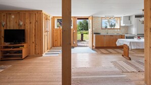 Et moderne interiør med trævægge, et fjernsyn, et køkken og udsigt udendørs.
