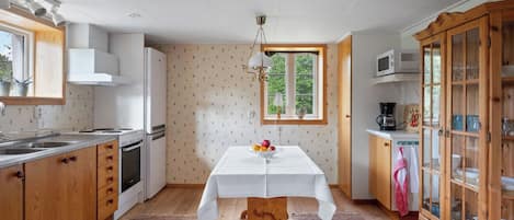 A kitchen with wooden cabinets, a white table, and a window with a view of greenery.