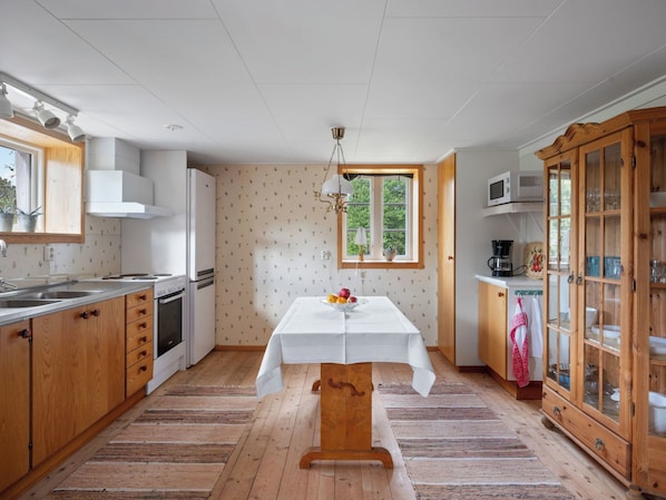 A kitchen with wooden cabinets, a white table, and a window with a view of greenery.
