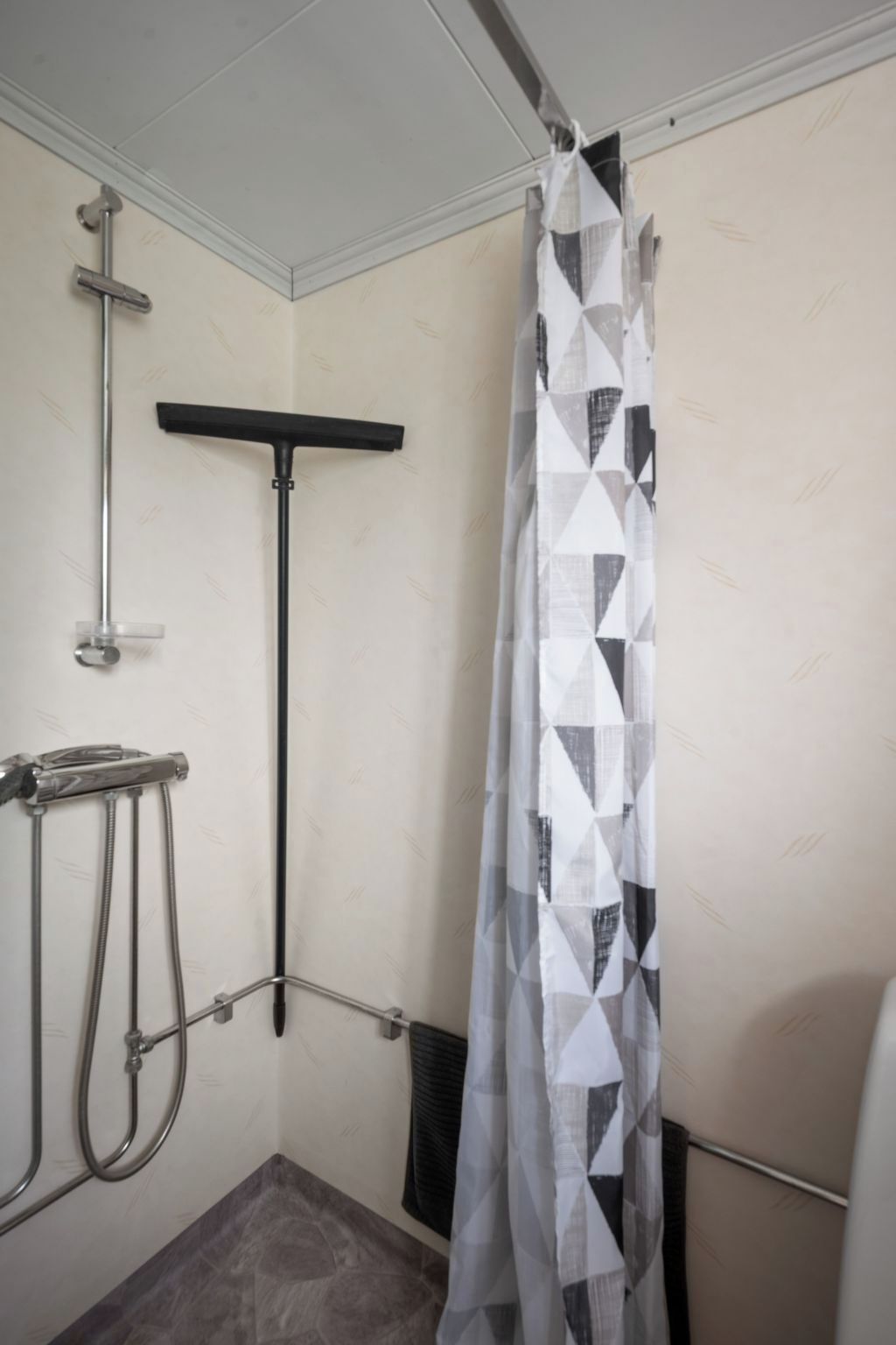 A shower area with a showerhead, handheld shower, and a curtain.