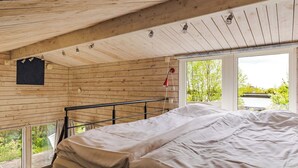 A wooden cabin bedroom with a bed, a window, and a view of greenery. - Ringenäs by Interhome (Halmstad)