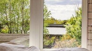 A room with a bed, a window with a view of trees and a building. - Ringenäs by Interhome (Halmstad)