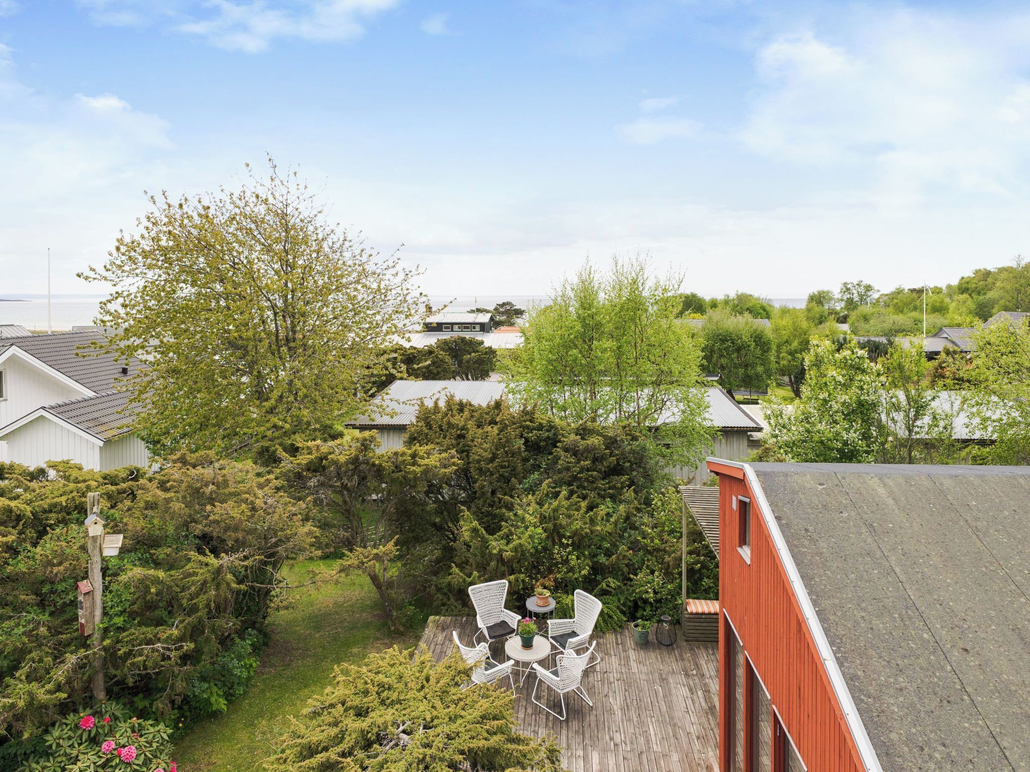 A residential area with houses, a wooden deck with chairs, and a red building.