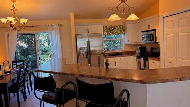 A kitchen with white cabinets, stainless steel appliances, and a large island with bar stools.