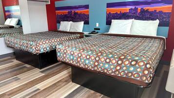 A hotel room with two beds, a cityscape mural on the wall, and a wooden floor.