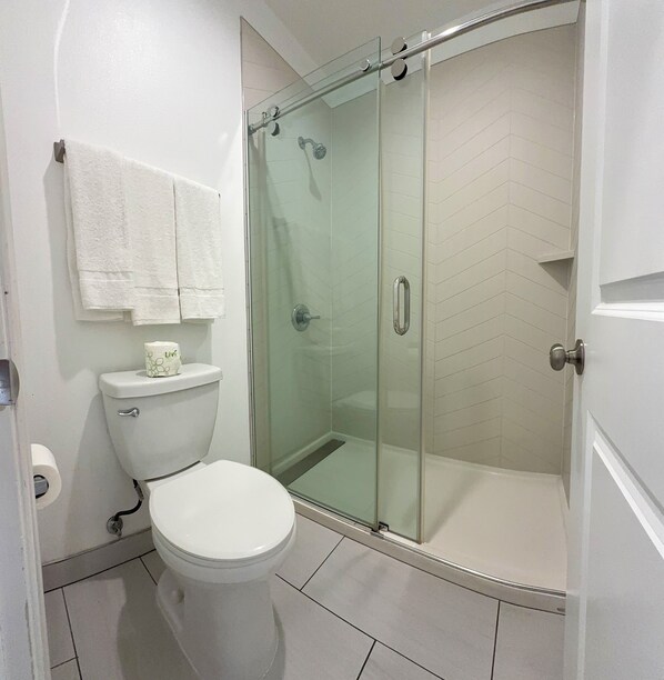 A bathroom with a toilet, a glass shower enclosure, and a towel rack. - La Casa Motel Burbank Airport - LA (Sun Valley)