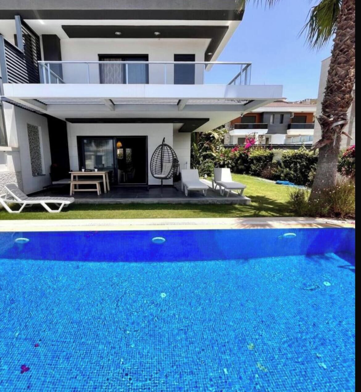 Une maison moderne à deux étages, dotée d’une piscine, d’un espace extérieur aménagé et d’une pelouse bien entretenue.