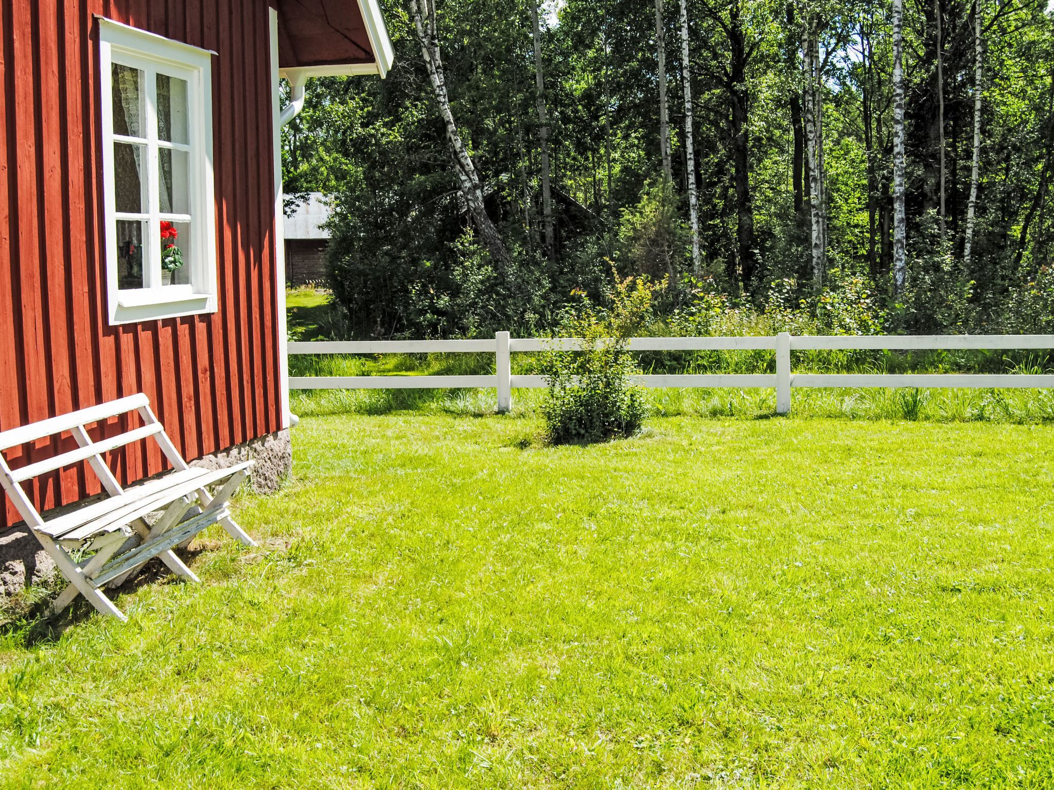 A red wooden building with a white window and bench outside.