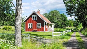 A red wooden house with a white porch and a white fence.
