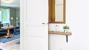 A white door with a brass handle, a small shelf with a heart-shaped decoration, and a mirror above it.