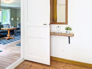Eine weiße Tür mit Messinggriff, eine kleine Ablage mit Herzdeko und ein Spiegel darüber.