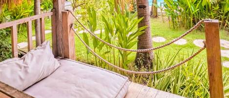 A wooden deck with a bed and a rope barrier.