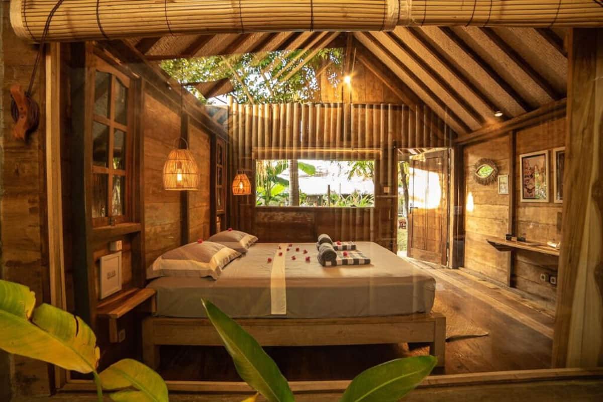 Una habitación de madera con una cama, una ventana y una estantería en la pared.