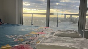 A bedroom with a large window, a bed with a floral bedspread, and a white blanket.