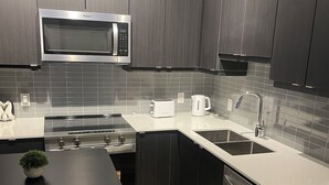 A modern kitchen with dark wood cabinets, a stainless steel microwave, a toaster, and a dishwasher.