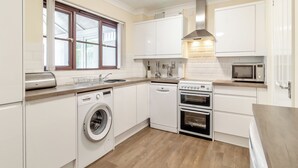 A compact kitchen with a washing machine, two ovens, a microwave, and a sink. - 4 bedroom accommodation in Sea Palling (Sea Palling)