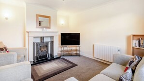 Ein Wohnzimmer mit Kamin, Flachbildfernseher und Bücherregal.