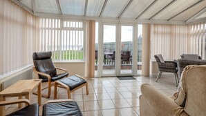 Una veranda luminosa con vista su una zona verde, un tavolo da pranzo e diverse sedie.