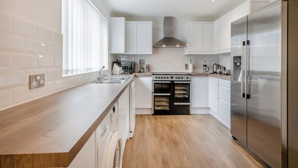 A modern kitchen with white cabinetry, a stainless steel refrigerator, a built-in oven, and a dishwasher. - 4 bedroom accommodation in Sea Palling (Sea Palling)