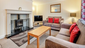 A living room with a fireplace, sofa, and TV. - 4 bedroom accommodation in Sea Palling (Sea Palling)