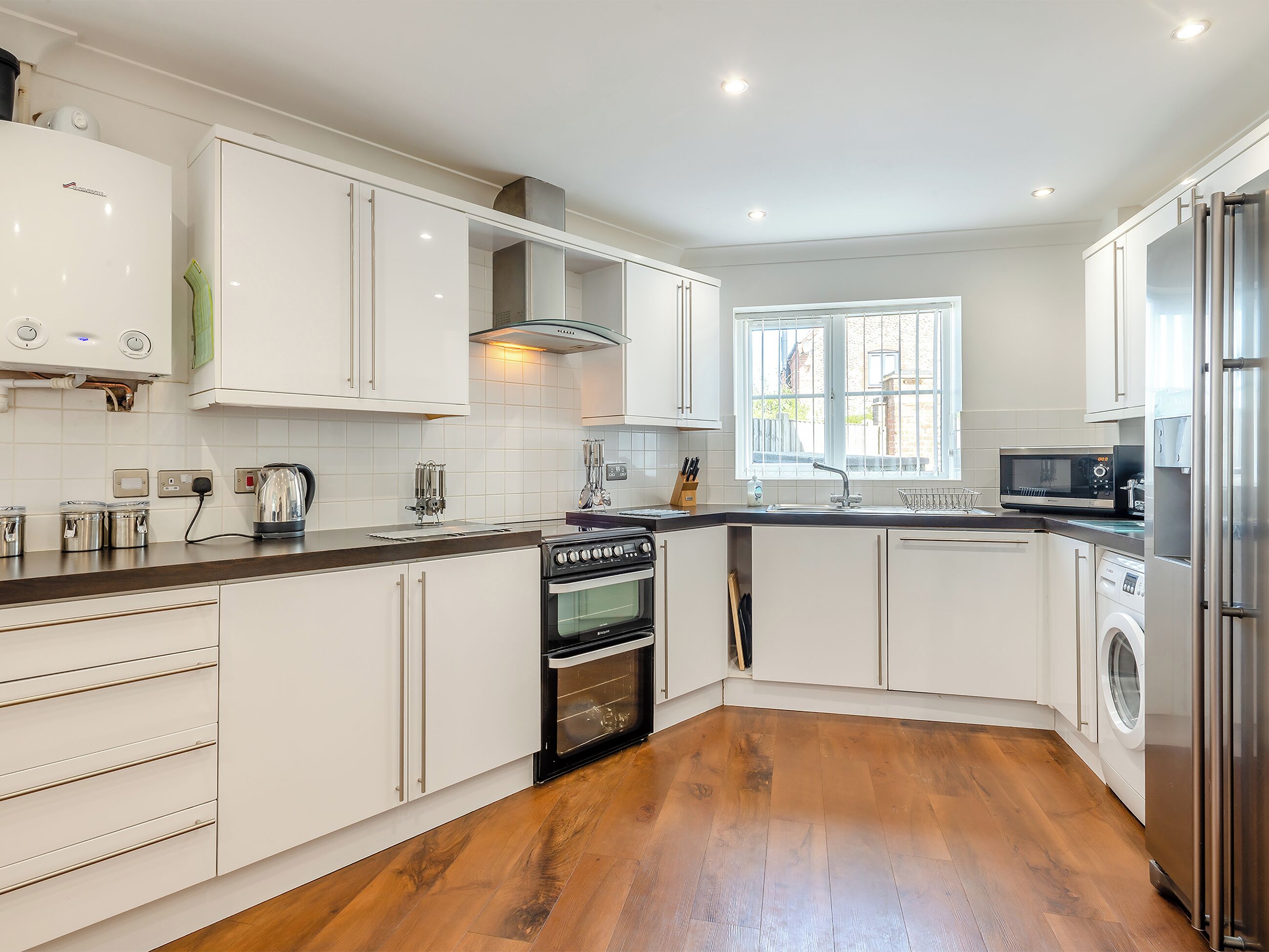 Een moderne keuken met witte kasten, een ingebouwde oven, een magnetron en een wasmachine.